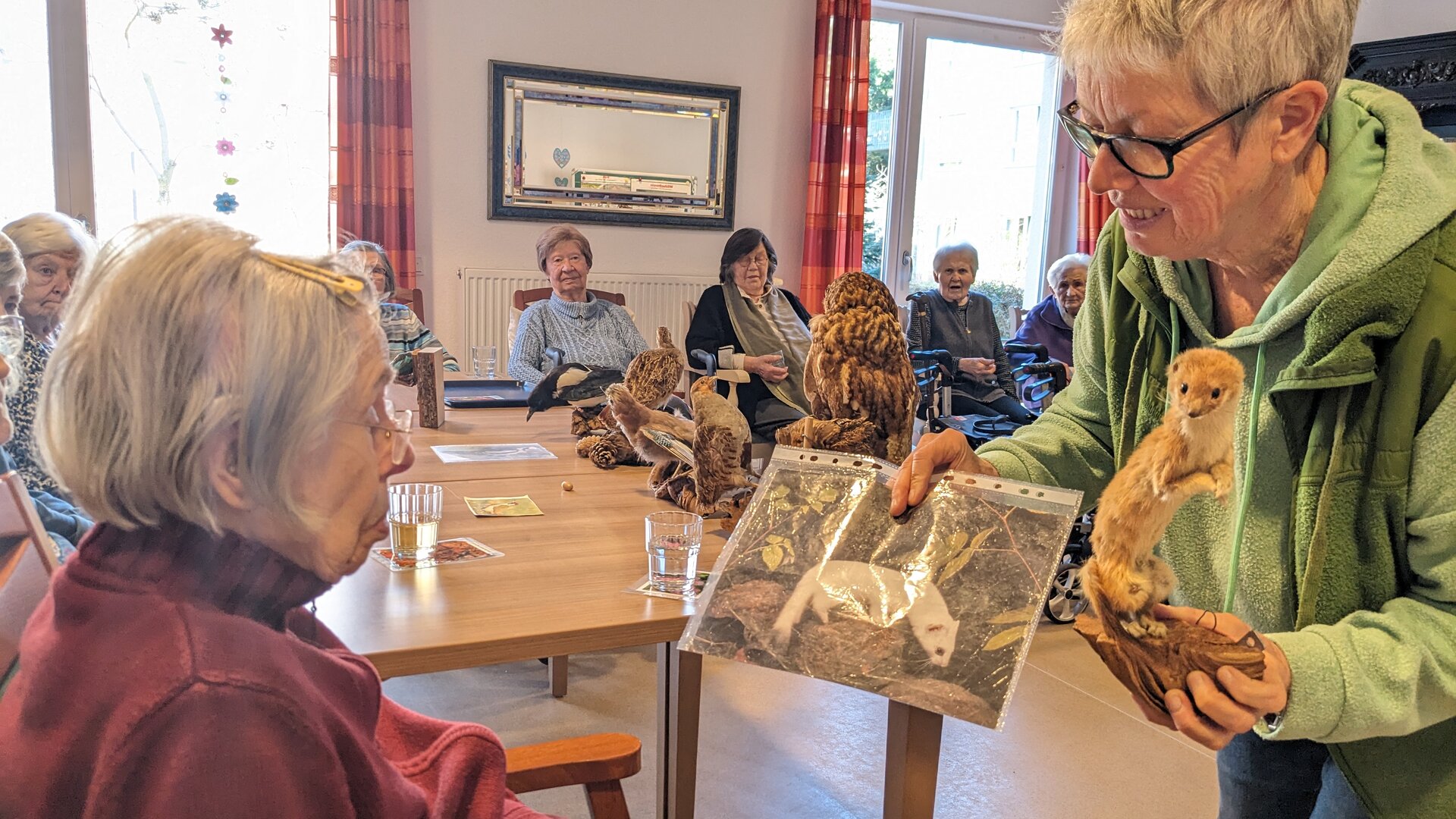Naturführerin zeigt Gästen Bild von Hermelin
