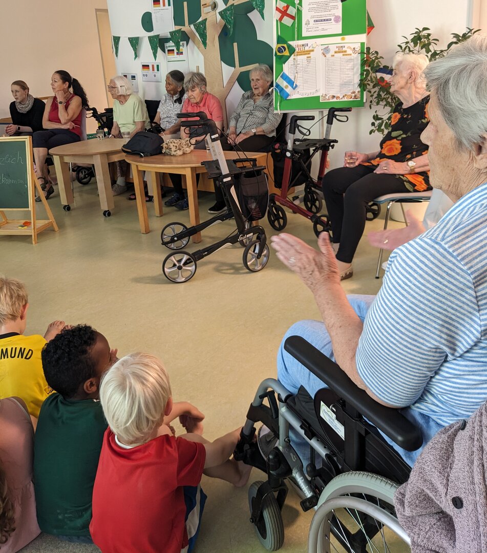 Kinder und Senioren im Stuhlkreis, klatschend